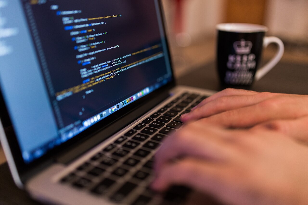 A programmer typing code on a laptop
